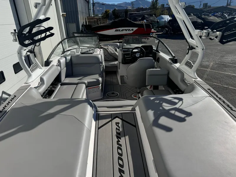 Slide: The Image of 2022 Moomba Mondo boat interior with seating and steering wheel, parked outdoors. - 5