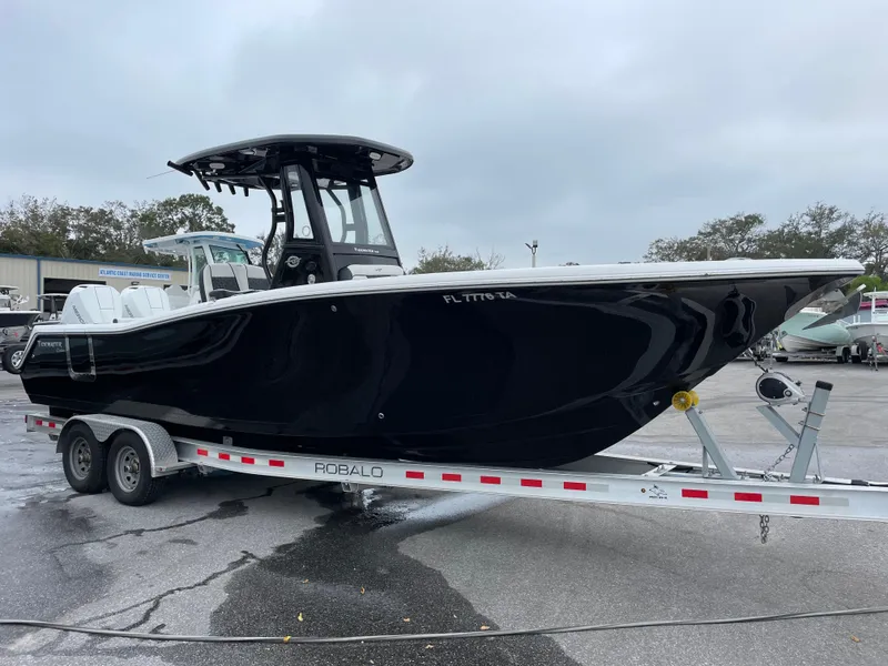 Slide: The Image of 2021 Tidewater 272 CC Adventure boat on trailer, black hull, parked outdoors. - 2