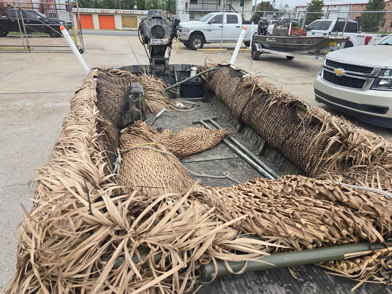 Slide: The Image of Camouflaged Custom Shallow 16 boat, 2016 model, parked in a lot with vehicles nearby. - 2