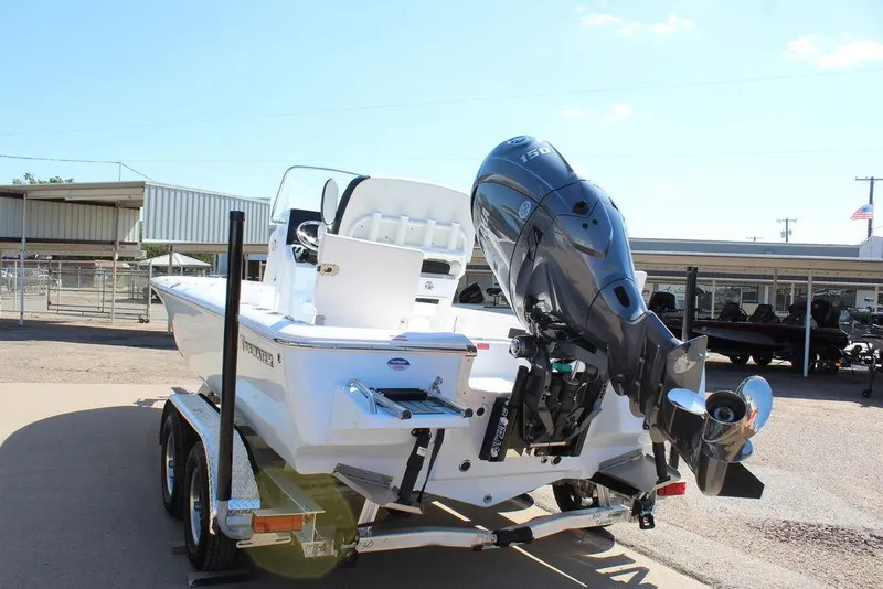 Slide: The Image of 2025 Tidewater 2110 Bay Max boat on trailer with outboard motor, parked outdoors. - 6