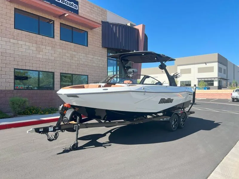 Slide: The Image of 2025 Malibu 23 LSV boat on trailer, parked outside a modern building. - 12