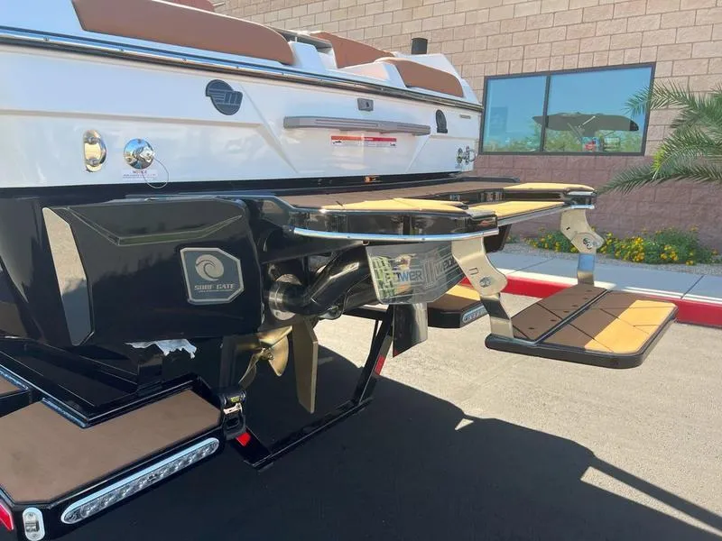 Slide: The Image of 2025 Malibu 23 LSV boat rear view with swim platform in a sunny outdoor setting. - 25