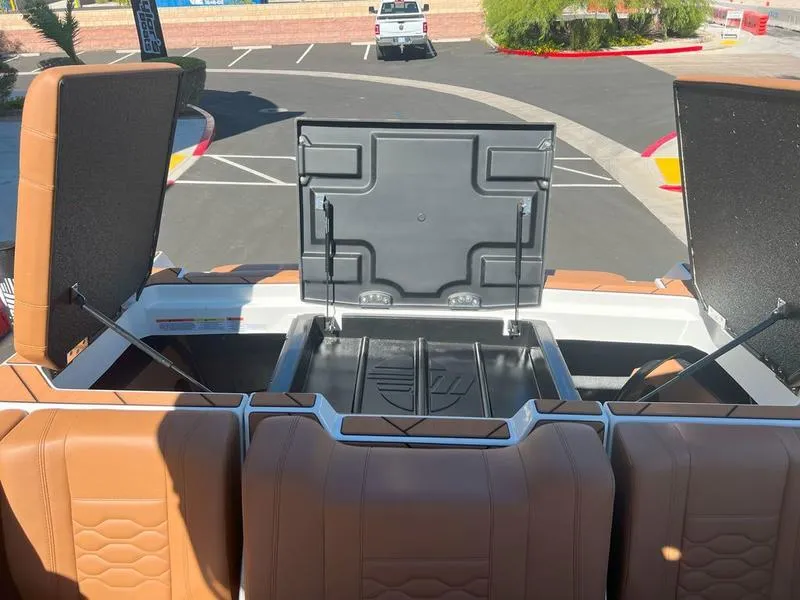 Slide: The Image of 2025 Malibu 23 LSV boat with open storage compartments and tan seating. - 34