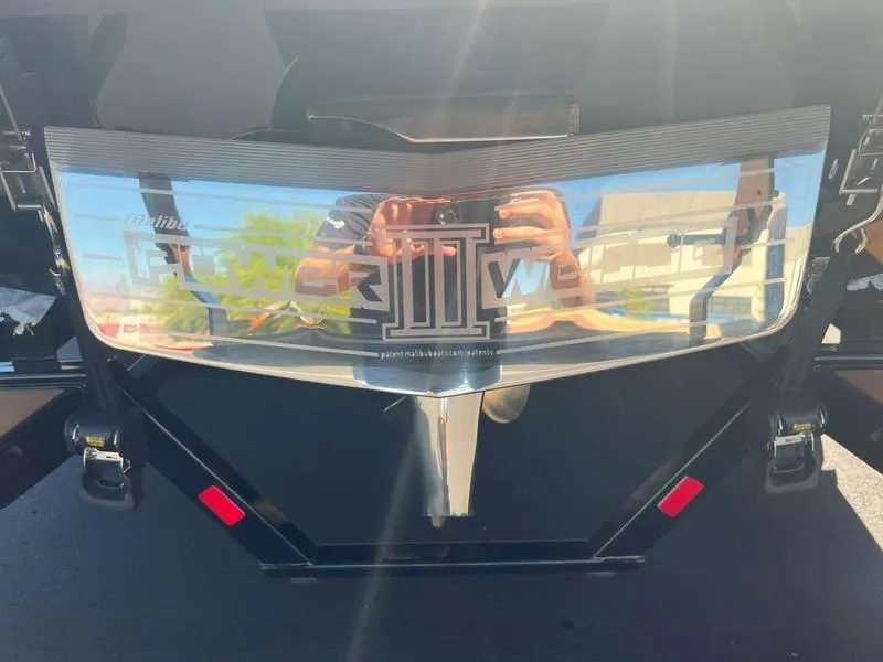 Slide: The Image of 2025 Malibu 23 LSV boat rear view with reflective surface and logo. - 36