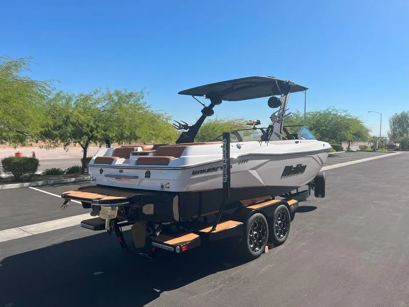 Slide: The Image of 2025 Malibu 23 LSV boat on trailer, parked on sunny street. - 6