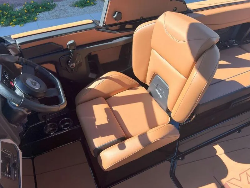 Slide: The Image of 2025 Axis A225 boat interior with tan leather seating and steering wheel. - 14