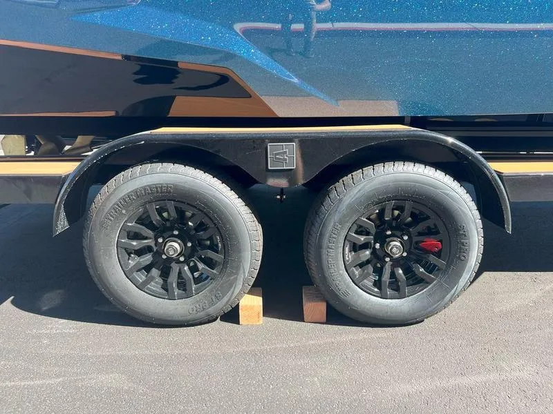 Slide: The Image of 2025 Axis A225 trailer wheels on asphalt, secured with wooden blocks. - 16