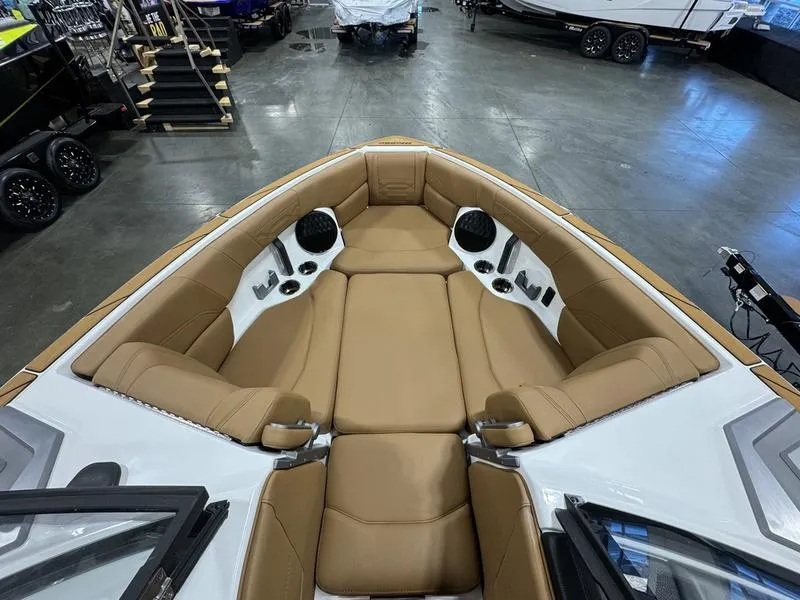 Slide: The Image of 2024 Malibu 25 LSV boat interior with tan seating and speakers in showroom. - 10
