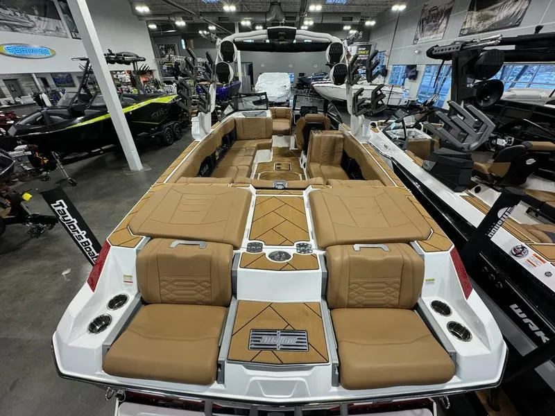 Slide: The Image of 2024 Malibu 25 LSV boat interior with tan seating in showroom. - 3
