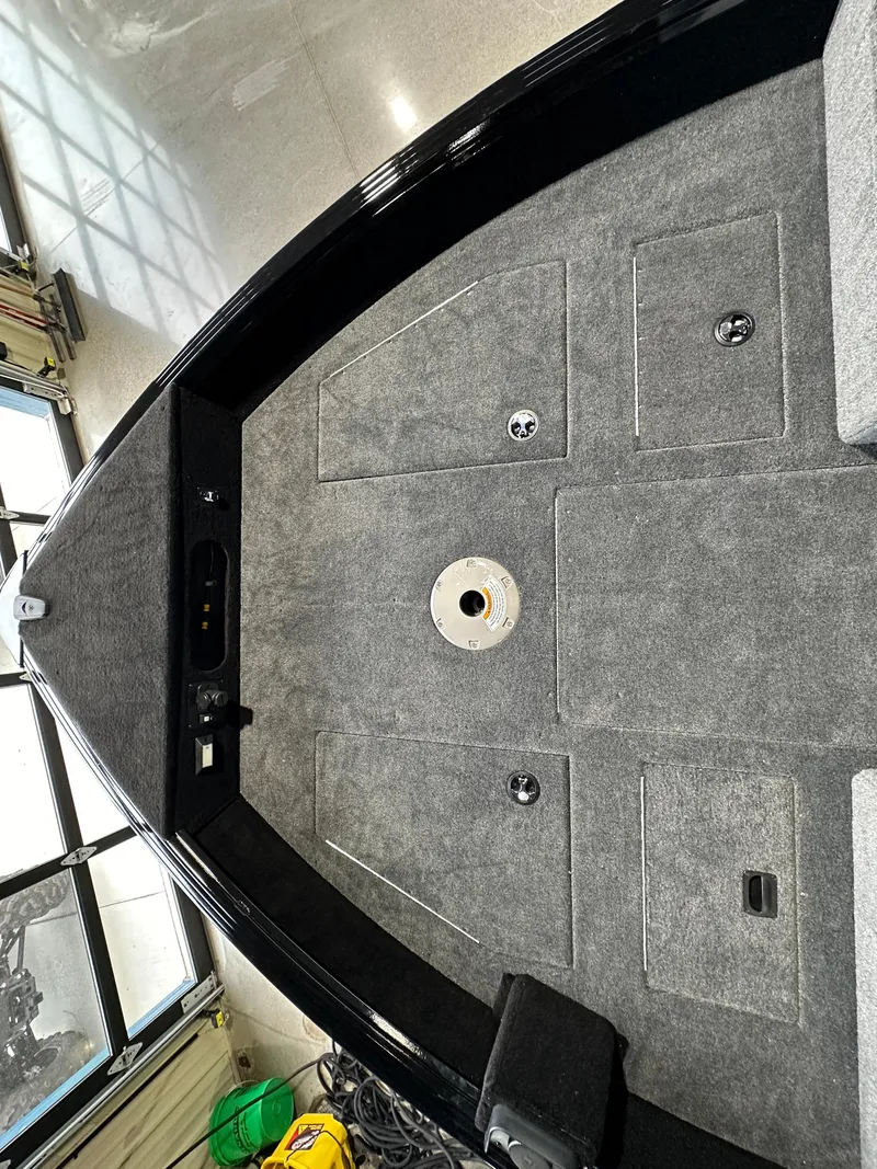 Slide: The Image of 2025 Smoker Craft Adventurer 188 DC boat interior with carpeted deck and storage compartments. - 3