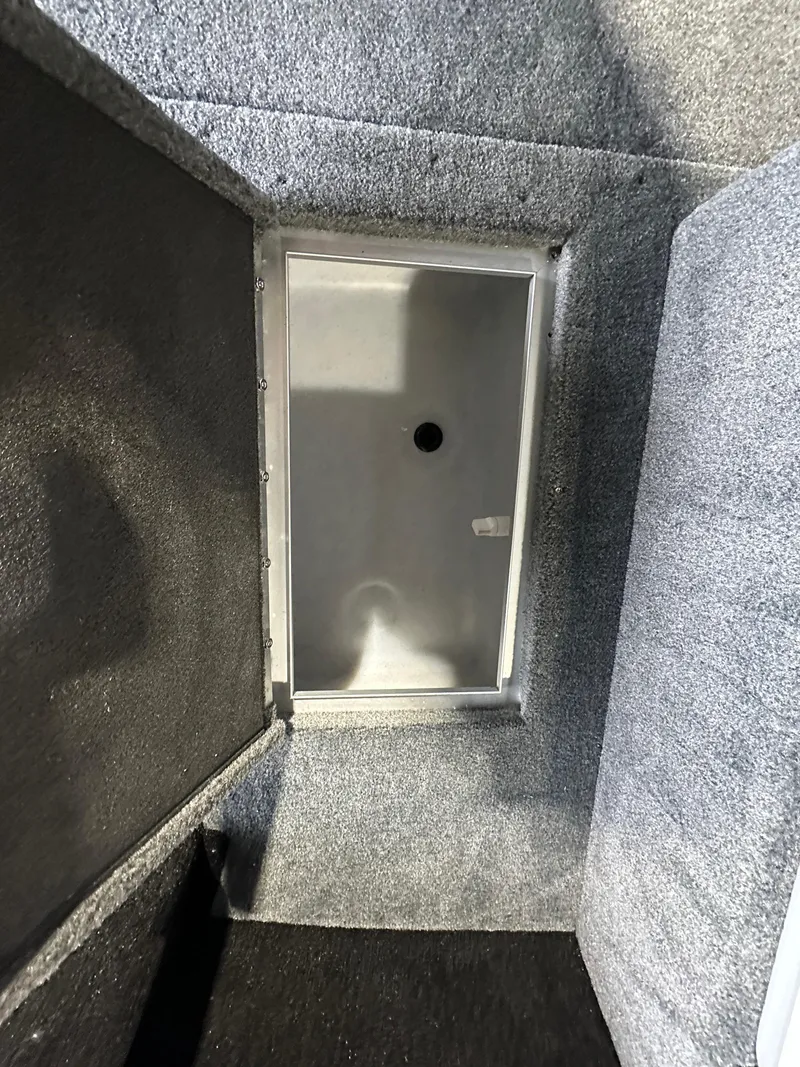 Slide: The Image of 2025 Smoker Craft Adventurer 188 DC boat storage compartment with gray carpet interior. - 4