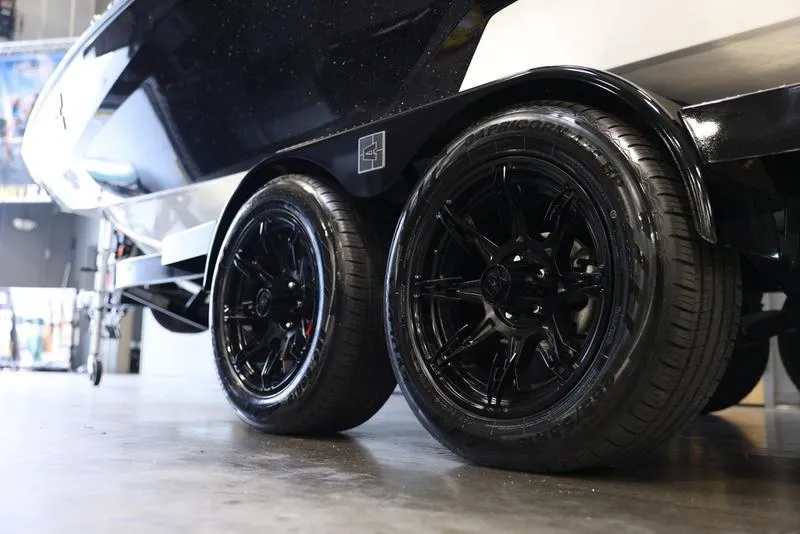 Slide: The Image of 2024 Axis A225 boat trailer with sleek black wheels in a showroom. - 15