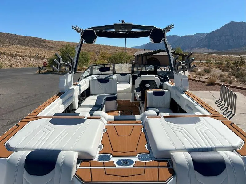 Slide: The Image of 2025 Malibu 25 LSV boat with luxurious seating and sleek design in a scenic desert setting. - 10