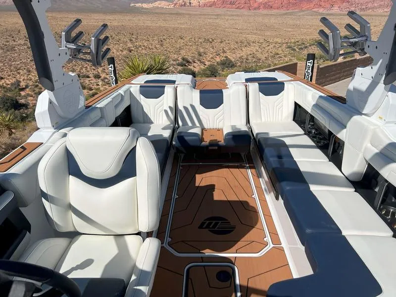 Slide: The Image of 2025 Malibu 25 LSV boat interior with white seating and desert landscape background. - 12