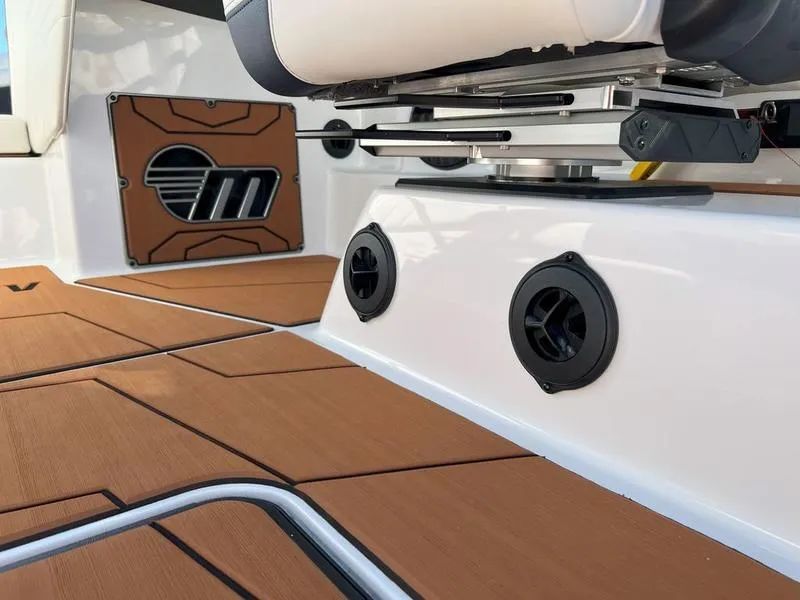 Slide: The Image of 2025 Malibu 25 LSV boat interior with brown flooring and seating details. - 15