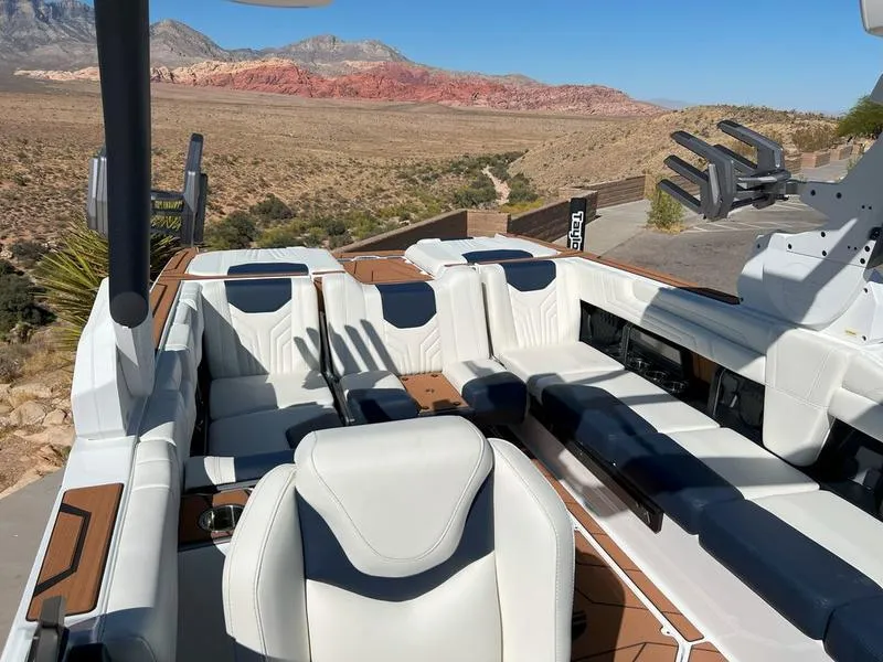 Slide: The Image of 2025 Malibu 25 LSV boat interior with white seating, set against a desert landscape. - 19