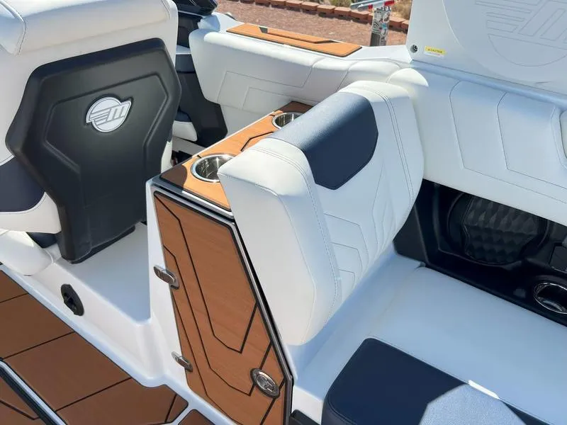 Slide: The Image of 2025 Malibu 25 LSV boat interior with white and tan seating, cup holders, and sleek design. - 24