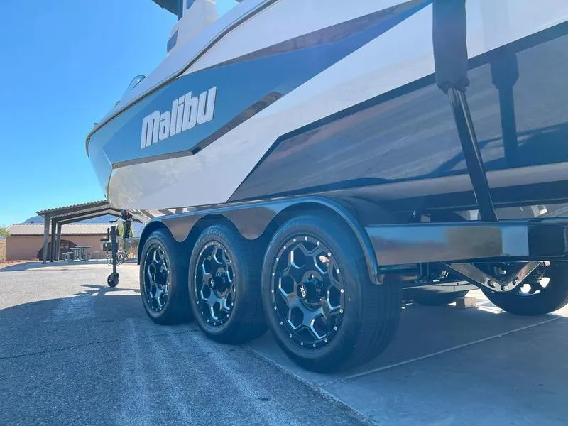 Slide: The Image of 2025 Malibu 25 LSV boat on a triple-axle trailer, parked outdoors. - 6