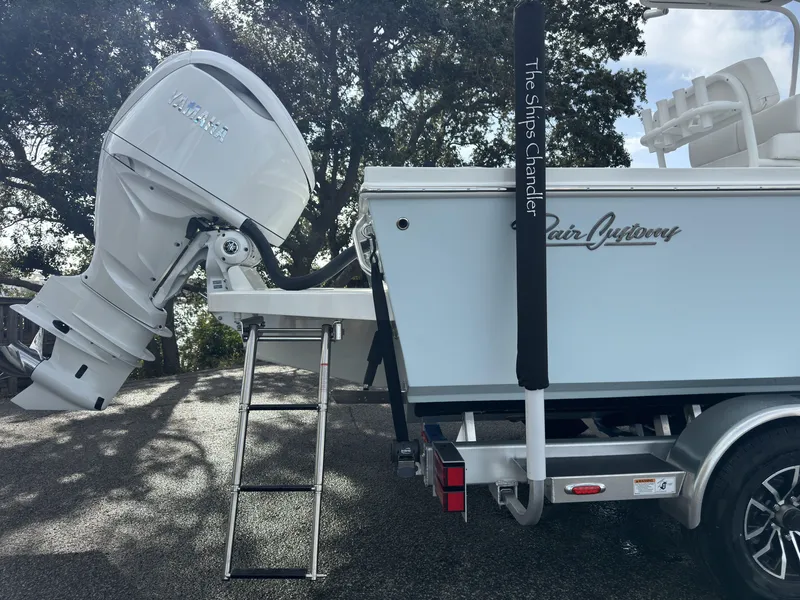 Slide: The Image of 2025 Pair Customs 24DV boat with Yamaha outboard motor and ladder, parked outdoors. - 18