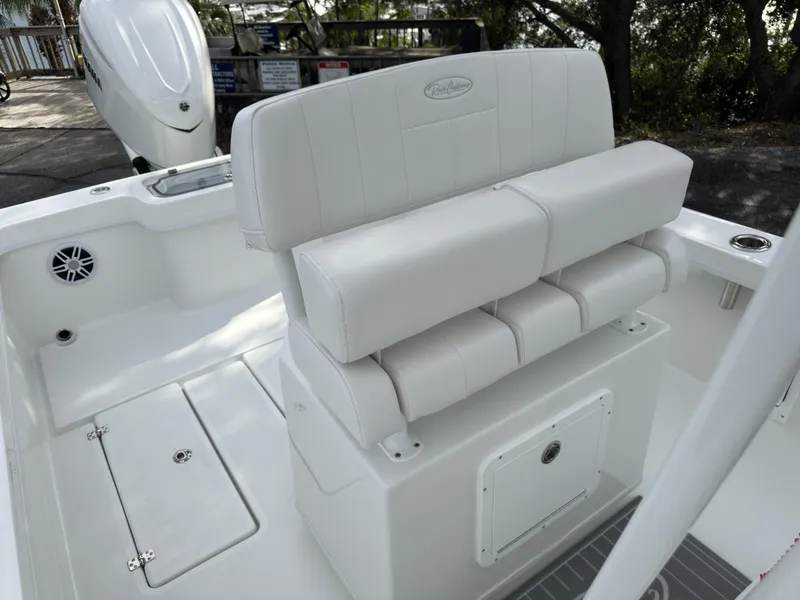 Slide: The Image of 2025 Pair Customs 24DV boat interior with white cushioned seating and storage compartment. - 24