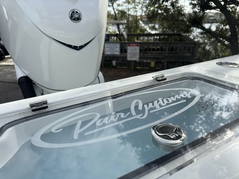 Slide: The Image of 2025 Pair Customs 24DV boat with Yamaha engine, docked near a wooded area. - 3