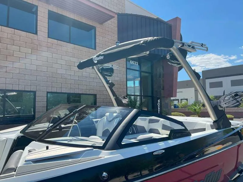Slide: The Image of 2021 Malibu 22 LSV boat parked outside a modern building under a clear blue sky. - 10
