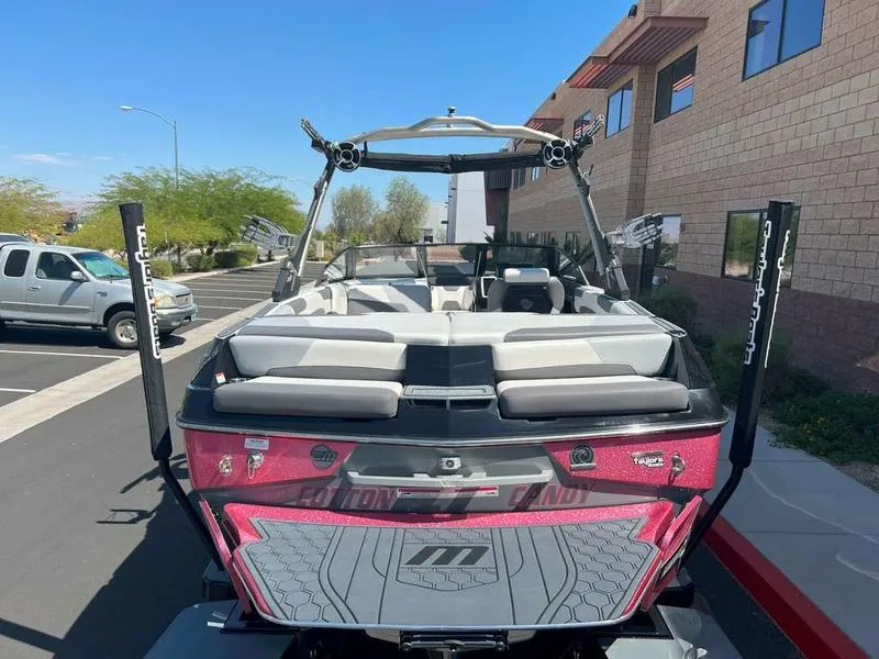 Slide: The Image of 2021 Malibu 22 LSV boat with pink detailing, parked outdoors. - 11