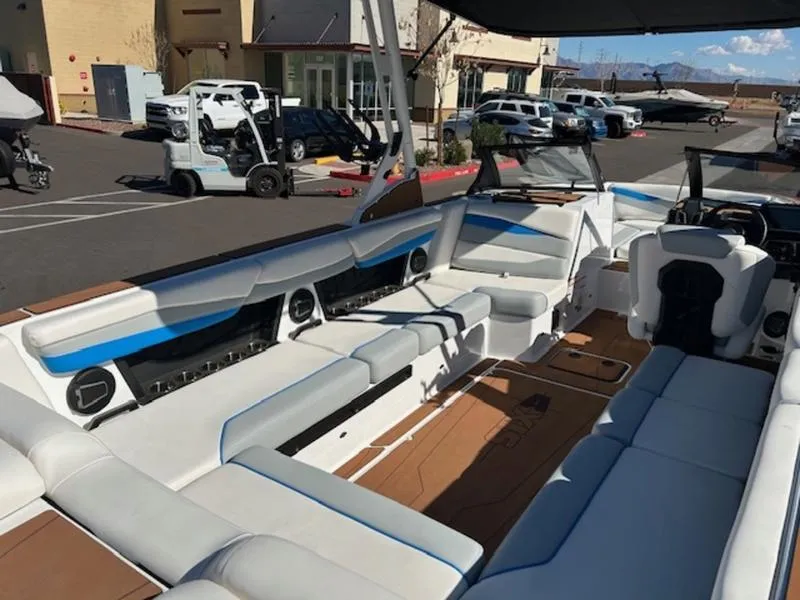 Slide: The Image of 2025 Axis A245 boat interior with white and blue seating in a parking lot. - 16