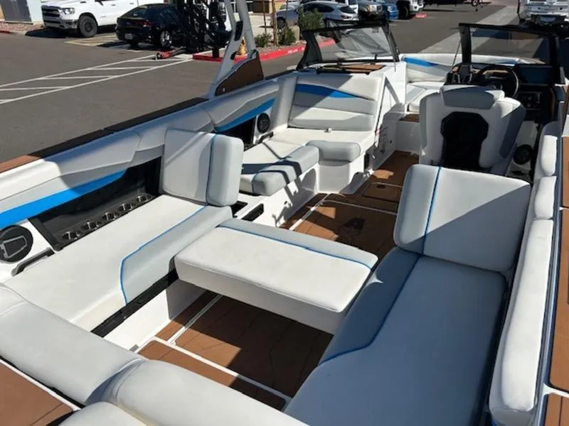 Slide: The Image of 2025 Axis A245 boat interior with white and blue seating, parked in a lot. - 17