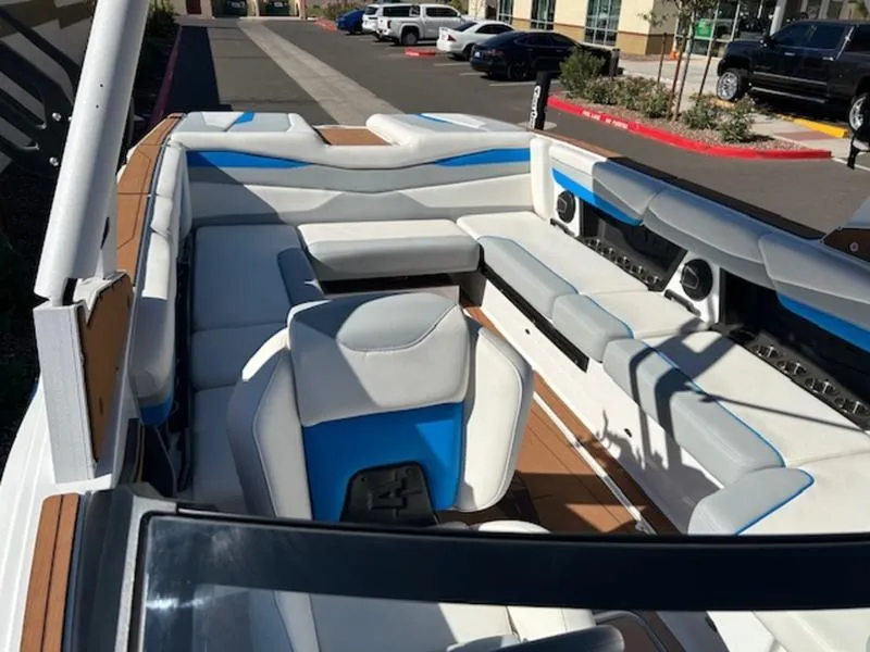 Slide: The Image of 2025 Axis A245 boat interior with white and blue seating, parked outdoors. - 18