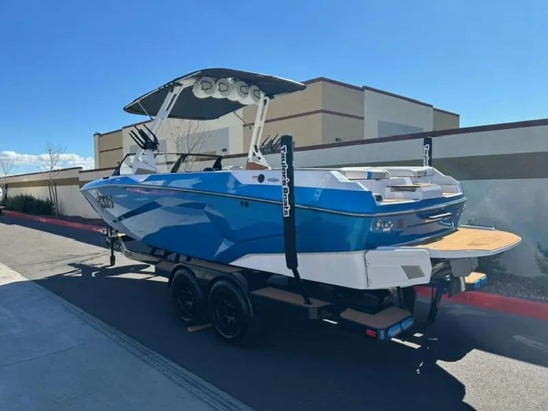 Slide: The Image of 2025 Axis A245 boat on trailer, blue and white design, parked outdoors. - 4