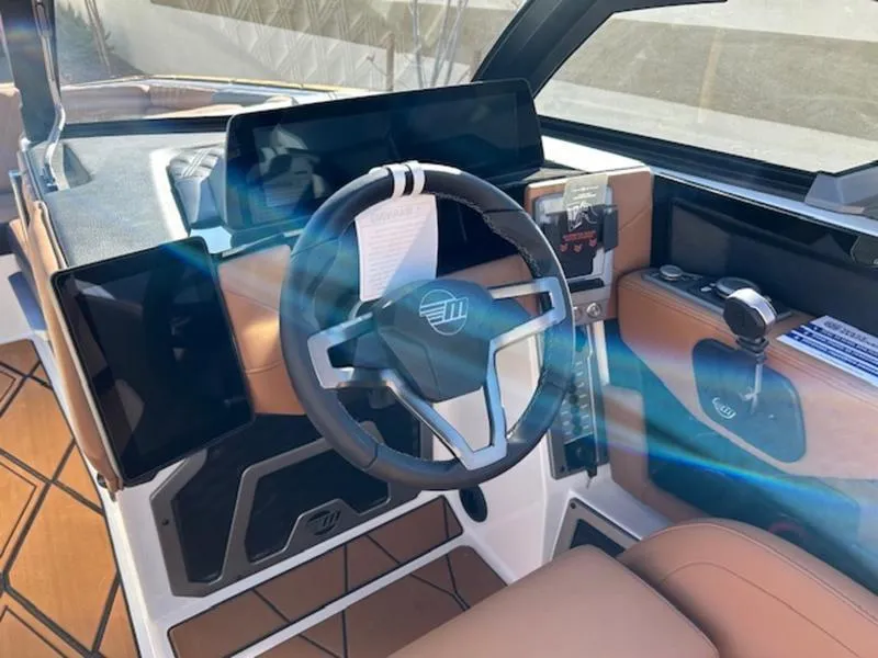 Slide: The Image of 2025 Malibu M242 boat cockpit with modern steering wheel and dashboard controls. - 14