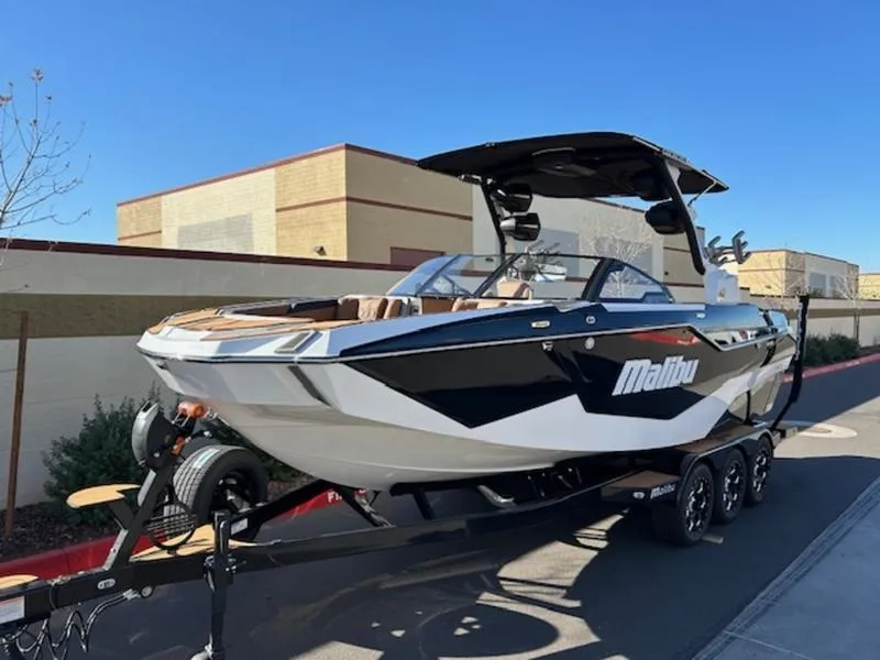 Slide: The Image of 2025 Malibu M242 boat on trailer, sleek design, parked outdoors. - 2