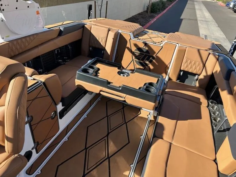 Slide: The Image of 2025 Malibu M242 boat interior with tan leather seating and a central table. - 23