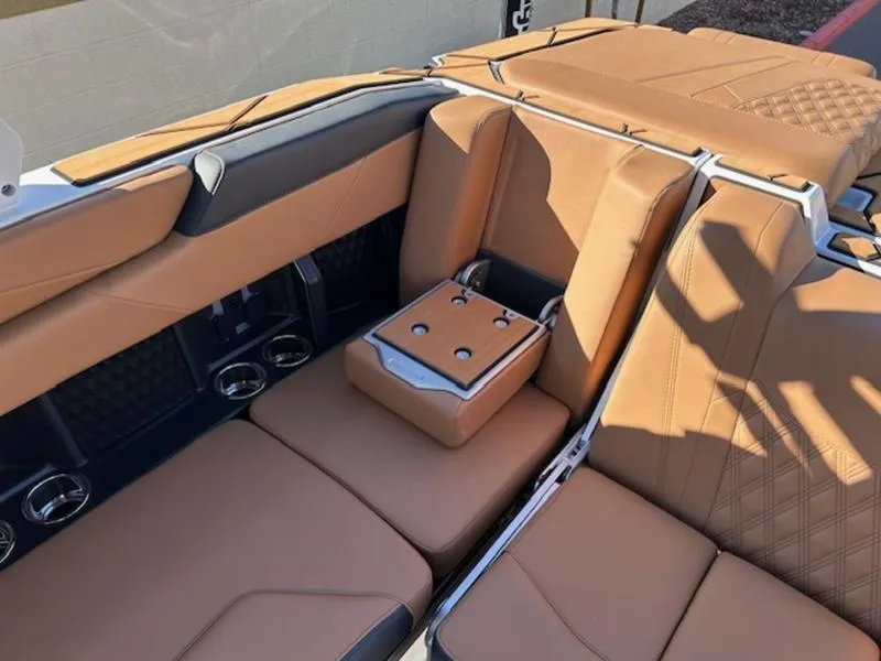 Slide: The Image of 2025 Malibu M242 boat interior with tan leather seating and cup holders. - 24