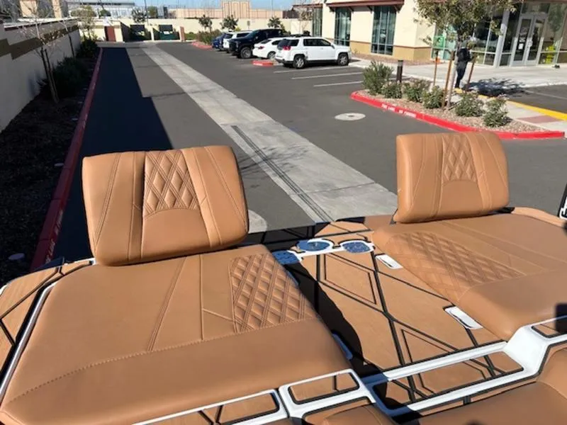 Slide: The Image of 2025 Malibu M242 boat with tan leather seats in a parking lot. - 31