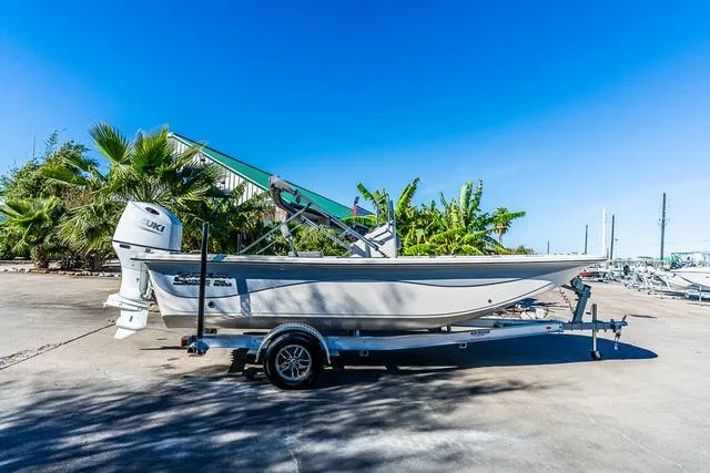 Slide: The Image of 2025 Carolina Skiff 21LS boat on trailer, parked outdoors under clear blue sky. - 1