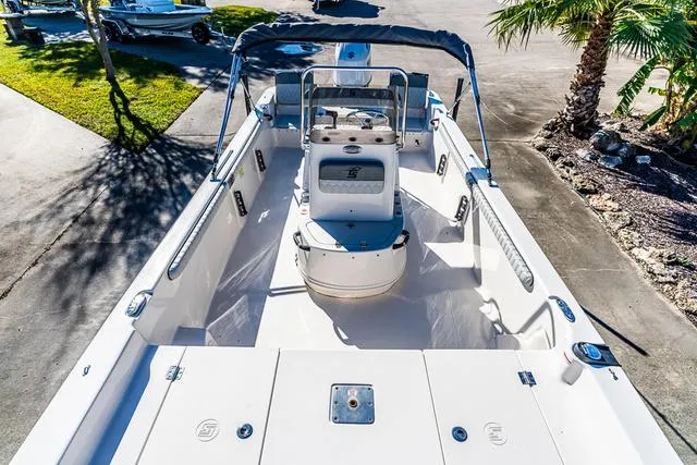 Slide: The Image of 2025 Carolina Skiff 21LS boat with seating and console, parked near palm trees. - 7