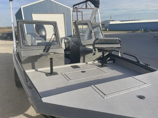 Slide: The Image of 2025 SeaArk Pro Cat 200 boat with spacious deck and seating, parked near blue storage buildings. - 11