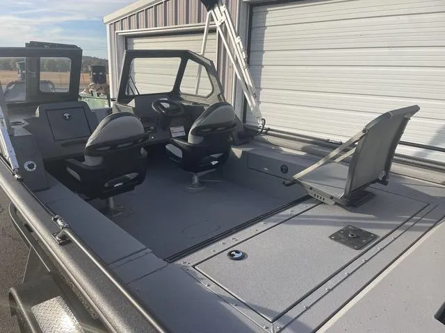 Slide: The Image of 2025 SeaArk Pro Cat 200 boat interior with seating and storage, parked near a garage. - 17