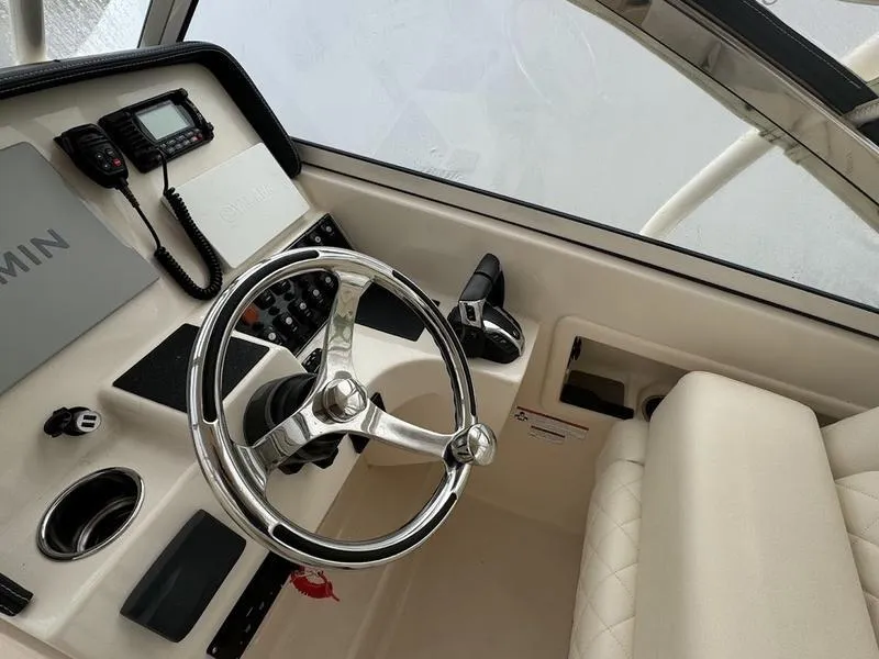 Slide: The Image of Interior of 2022 Grady-White 275 Freedom boat, featuring steering wheel and control panel. - 14