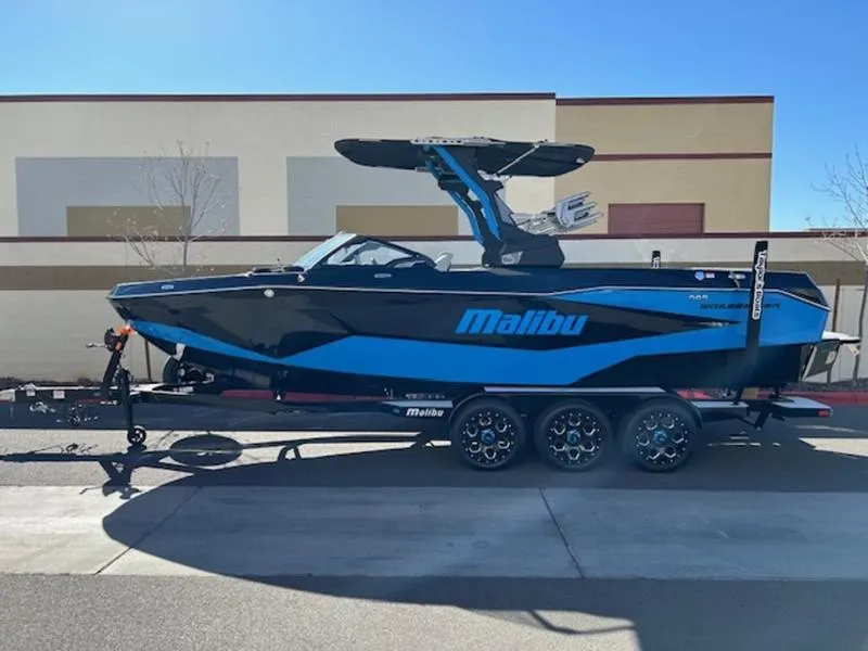 Slide: The Image of 2025 Malibu 25 LSV boat in blue and black on a trailer. - 1