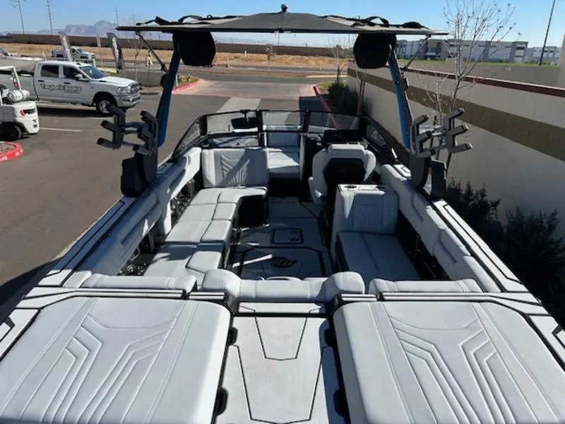 Slide: The Image of 2025 Malibu 25 LSV boat with spacious seating and sleek design in a parking lot. - 10