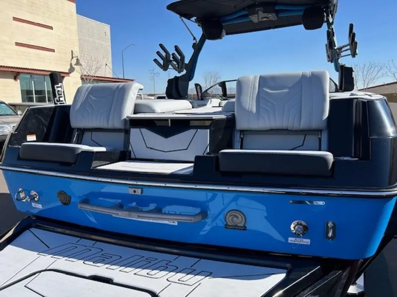 Slide: The Image of 2025 Malibu 25 LSV boat, blue exterior, luxury seating, docked outdoors. - 11