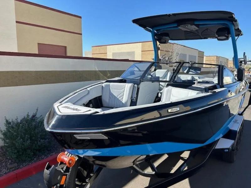 Slide: The Image of 2025 Malibu 25 LSV boat with sleek black and blue design, parked outdoors. - 9