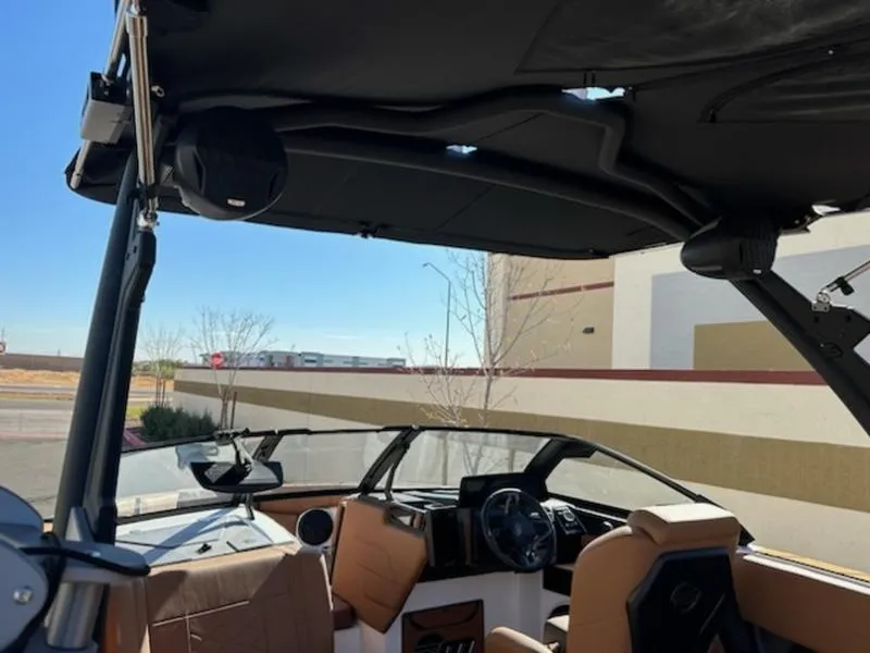 Slide: The Image of 2025 Malibu 22 LSV boat interior with tan seats and black canopy. - 13