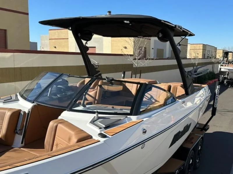 Slide: The Image of 2025 Malibu 22 LSV boat with sleek design and tan interior, parked outdoors. - 9