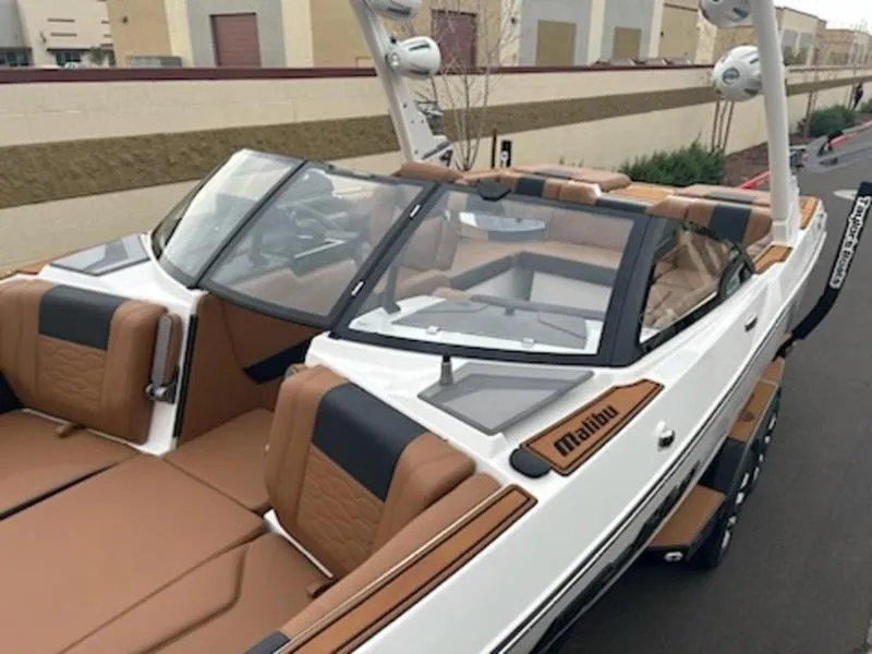 Slide: The Image of 2025 Malibu 22 MXZ boat with tan and black interior, parked outdoors. - 17