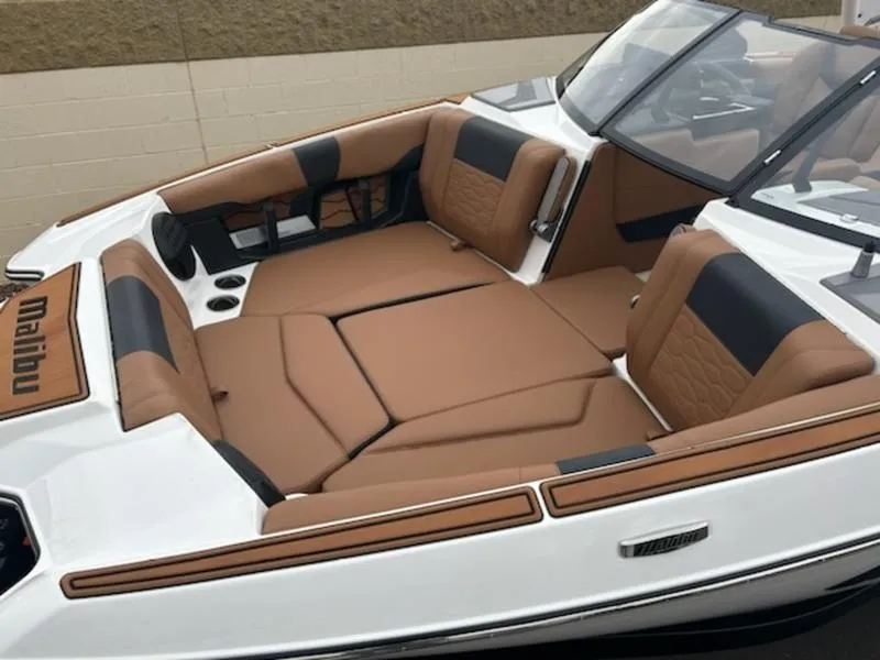 Slide: The Image of 2025 Malibu 22 MXZ boat interior with tan and black seating, cup holders, and sleek design. - 20