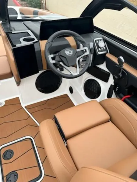 Slide: The Image of 2025 Malibu 22 MXZ boat interior with modern dashboard and tan seating. - 5